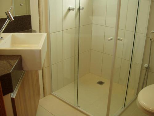 een glazen douche in een badkamer met een wastafel bij Jurerê - Canto Belo in Florianópolis