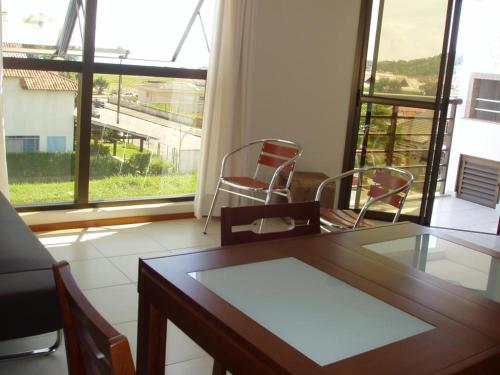 Un comedor con mesa y sillas y ventanas. en Jurerê - Canto Belo, en Florianópolis