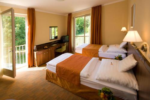 a hotel room with two beds and a balcony at Jankovich Hotel in Rácalmás