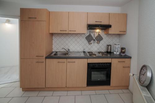 a kitchen with wooden cabinets and a sink and a stove at Designpension Traumschloss Hotel Garni in Wernigerode