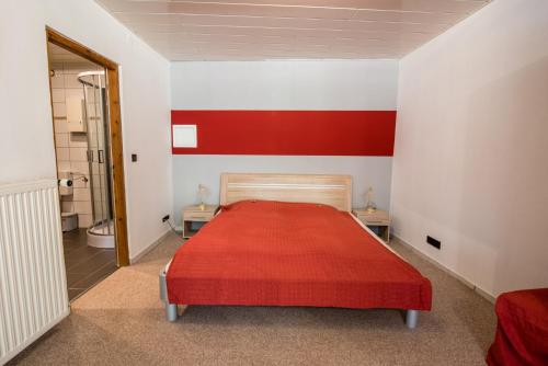 a red and white bedroom with a bed and a bathroom at Weinschlößchen im Weingut Roos in Ilbesheim