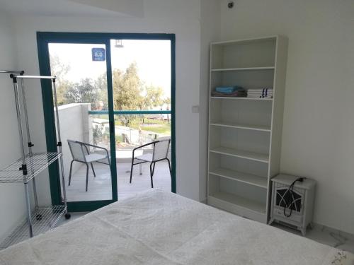 a bedroom with a bed and a balcony with chairs at Apartment By The Lake in Tiberias