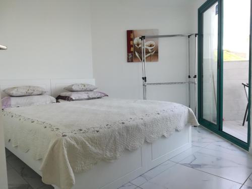 a white bedroom with a bed and a glass door at Apartment By The Lake in Tiberias