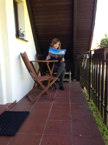 a woman sitting in a chair reading a book on a patio at Bernstein in Zingst