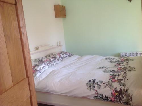 a bedroom with a bed with a floral blanket at ANVIL COTTAGE in Whitchurch
