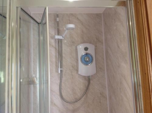 een douche met een douchekop in de badkamer bij ANVIL COTTAGE in Whitchurch