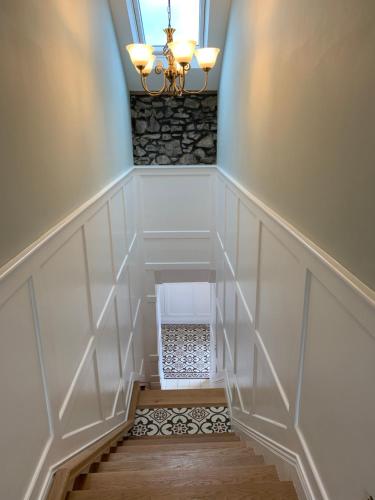 a hallway with a staircase with a chandelier at Biddy Ban’s in Carnmalin