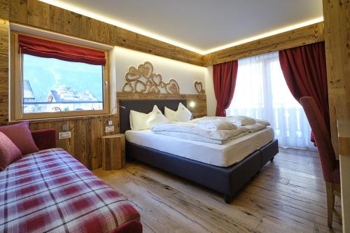 a bedroom with a large bed and a window at Cimon Dolomites Hotel in Predazzo