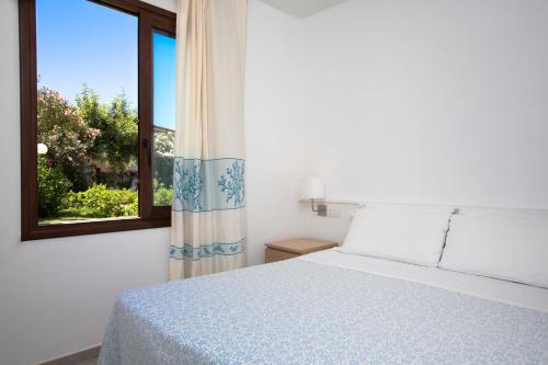 a bedroom with a bed and a window at Cormoran Residence in Villasimius