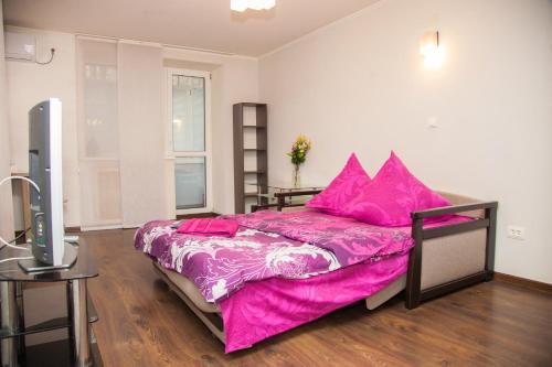 a bedroom with a bed with pink sheets and a television at Semi-luxury Apt on Ukrainskaya 43 Street in Zaporozhye