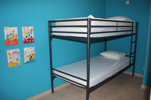 Ce lit se trouve dans un dortoir doté de 2 lits superposés et d'un mur bleu. dans l'établissement Résidence Atlantic, à Coxyde