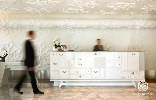 a man walking past a dresser in a room at Hôtel de Paris Saint-Tropez in Saint-Tropez