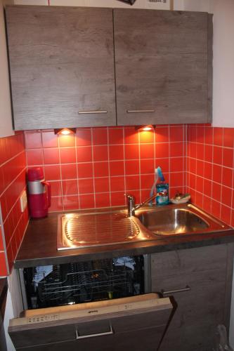 a kitchen with a sink and a red tiled wall at Résidence Atlantic in Koksijde