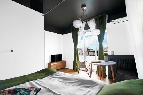 Schlafzimmer mit einem Bett, einem Tisch und einem Fenster in der Unterkunft Downtown by CityLife Suites in Bukarest