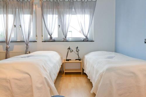 two beds in a room with two windows at Gästehaus Streich Refrath, Bergisch Gladbach in Bergisch Gladbach