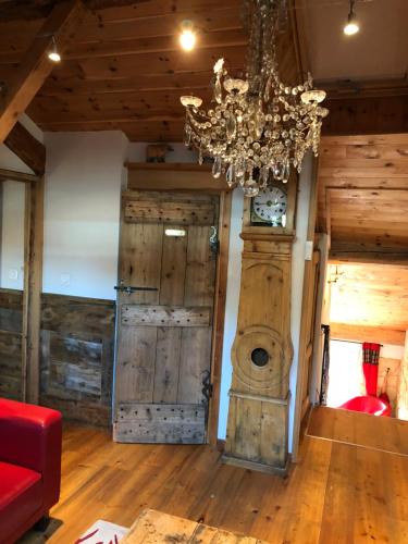 a chandelier hangs over a living room with wooden floors at Hôtel Restaurant de la Chaussée in Briançon