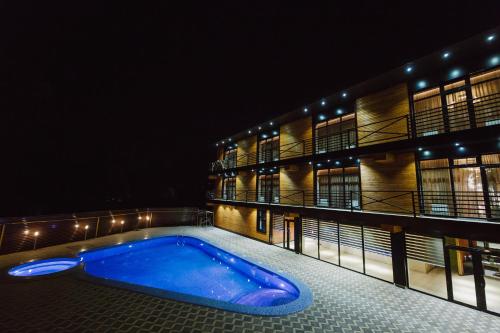 a swimming pool in front of a building at night at Barhat Hotel & SPA in Taraz