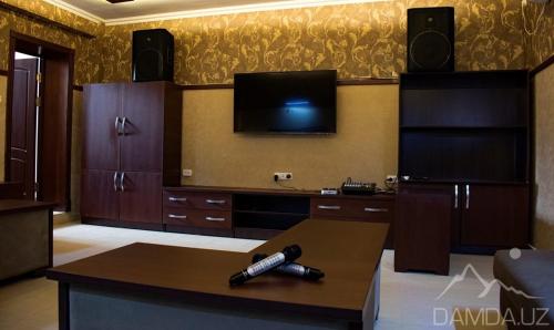 ein Wohnzimmer mit einem TV an der Wand und einem Tisch in der Unterkunft B&B Lake House Hotel in Yusufkhona