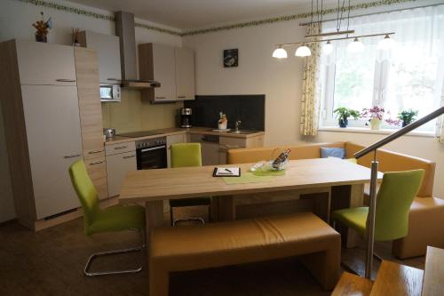 eine Küche und ein Esszimmer mit einem Holztisch und grünen Stühlen in der Unterkunft Zur Weinlaube in Mönchhof