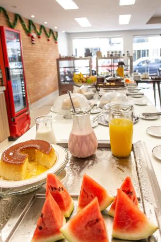 een tafel met plakjes watermeloen op borden en sinaasappelsap bij Panorama Convention Hotel in Coronel Fabriciano