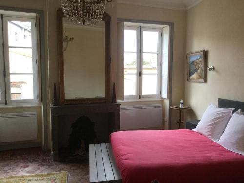 a bedroom with a red bed and two windows at Manoir d'Aubeterre in Marsat