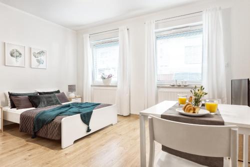 a white bedroom with a bed and a dining table at Apartamenty Tespis - Francuska Atal Park in Katowice