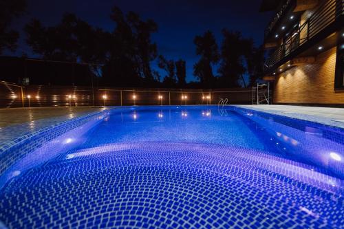 a large swimming pool at night with blue lighting at Barhat Hotel & SPA in Taraz