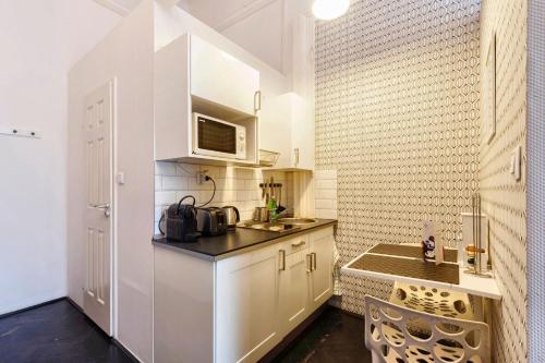 a small kitchen with white cabinets and a microwave at Adagio Hostel Basilica in Budapest