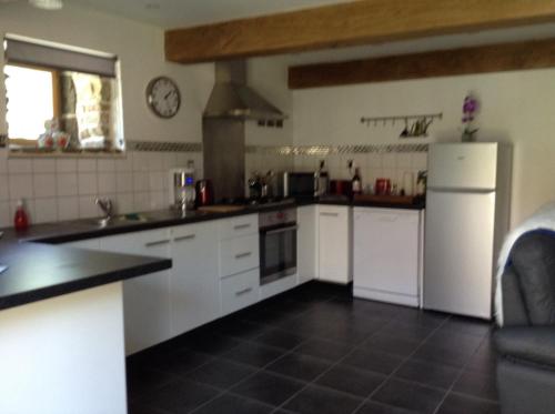 une grande cuisine avec des armoires et des appareils blancs dans l'établissement The Grange, à Les Portes du Coglais