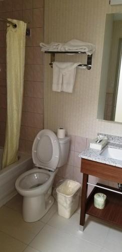a bathroom with a toilet and a sink and a mirror at Baymont by Wyndham Montreal Airport in Dorval