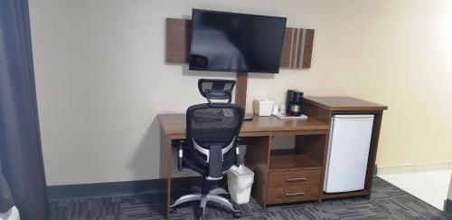a computer desk with a monitor and a chair at Baymont by Wyndham Montreal Airport in Dorval