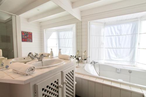 a white bathroom with a tub and a sink at El Caprichio in Gaucín