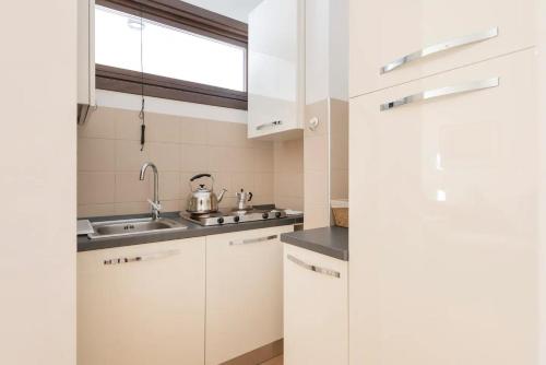 kuchnia z białymi szafkami, zlewem i oknem w obiekcie World Wide Bed San Giovanni w Rzymie