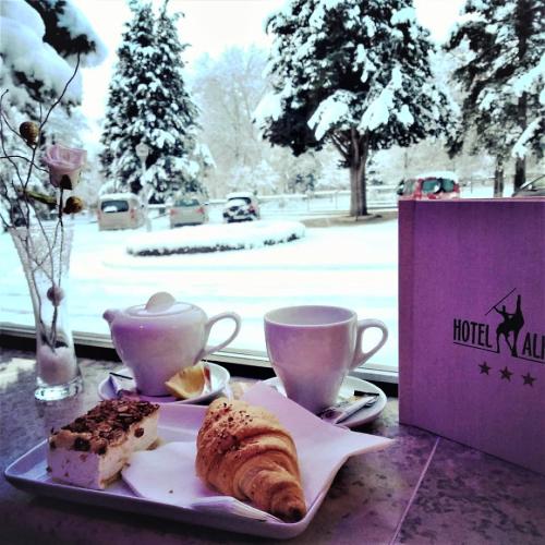 a table with a plate of pastries and cups of coffee at Hotel Alkar in Sinj