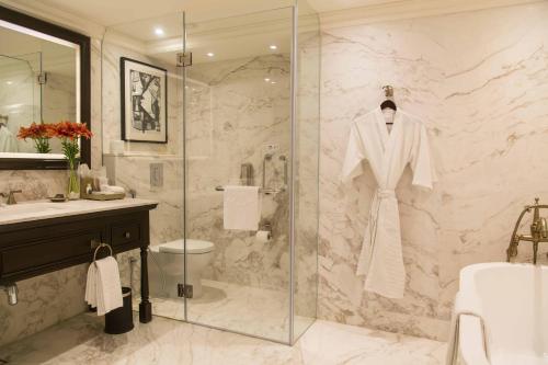 a bathroom with a shower with a white robe on a glass door at Taj Bengal in Kolkata
