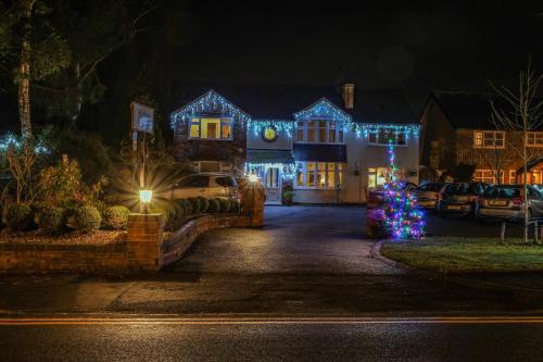 una casa decorada con luces de Navidad en un patio en The Hinton Guest House en Knutsford