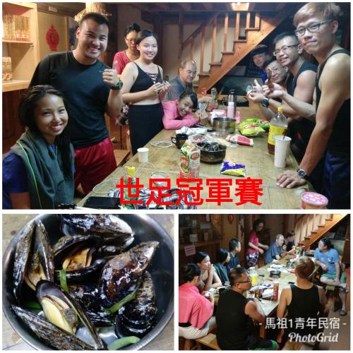 a group of people standing around a table with food at Matsu 1st Hostel in Nangan