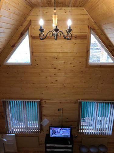 a room with two windows and a chandelier in a cabin at Veranda in Mykulychyn