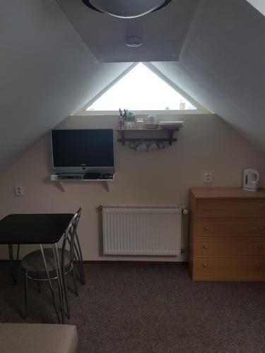 a attic room with a tv and a table and chair at BLUE PENSiON in Svoboda nad Úpou