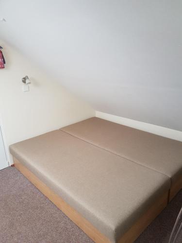 a bed in a room with a white wall at BLUE PENSiON in Svoboda nad Úpou