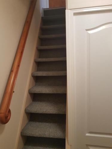 a staircase with grey carpeting and a wooden rail at BLUE PENSiON in Svoboda nad Úpou