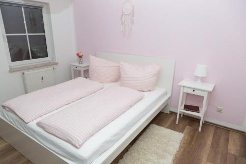 ein Bett mit rosa und weißer Bettwäsche und einem Fenster in der Unterkunft Ferienwohnung BadSaarowZentrum in Bad Saarow