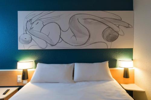 a bedroom with a bed with a painting above it at ibis Tours Nord in Tours