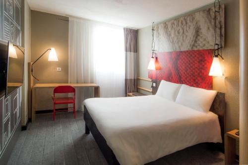 a hotel room with a large bed and a red chair at ibis Tours Nord in Tours