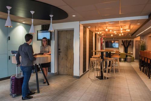 a man and a woman standing at a counter in a restaurant at ibis Tours Nord in Tours