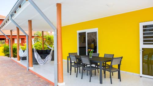 a patio with a black table and chairs and a yellow wall at Finisterre Curaçao in Sabana Westpunt