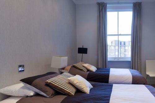 2 camas en una habitación de hotel con ventana en Linden Gardens, en Londres