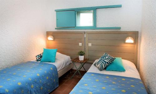 聖特羅佩的住宿－Village Vacances de Ramatuelle - Les sentier des pins，客房配有两张带蓝色枕头的床。