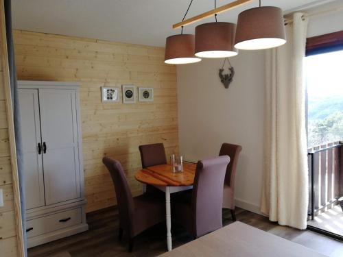 uma sala de jantar com uma mesa e cadeiras e uma janela em Bel appartement cosy - PIED DES PISTES avec local à ski - 6 personnes em Montclar