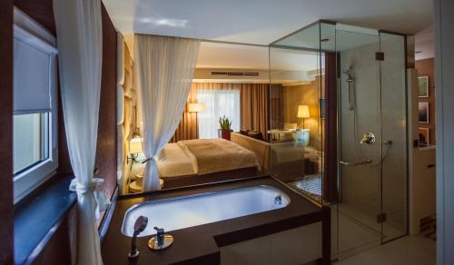 a bathroom with a tub and a bed and a shower at Grand Hotel Boutique in Rzeszów